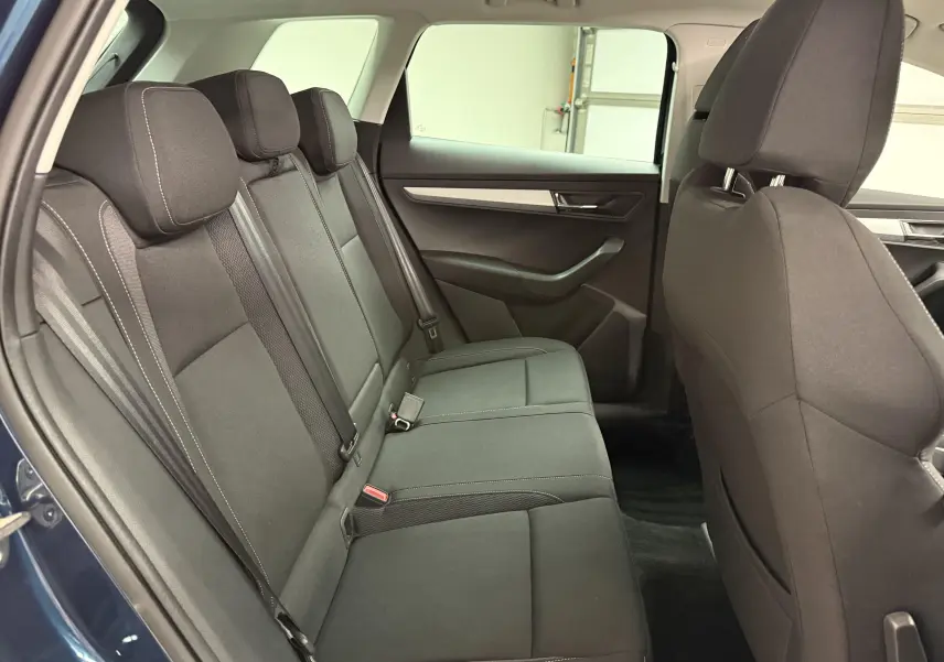 Vue intérieure côté gauche des sièges arrière noirs du Skoda Karoq 2023 bleu lave avec garnitures sobres.