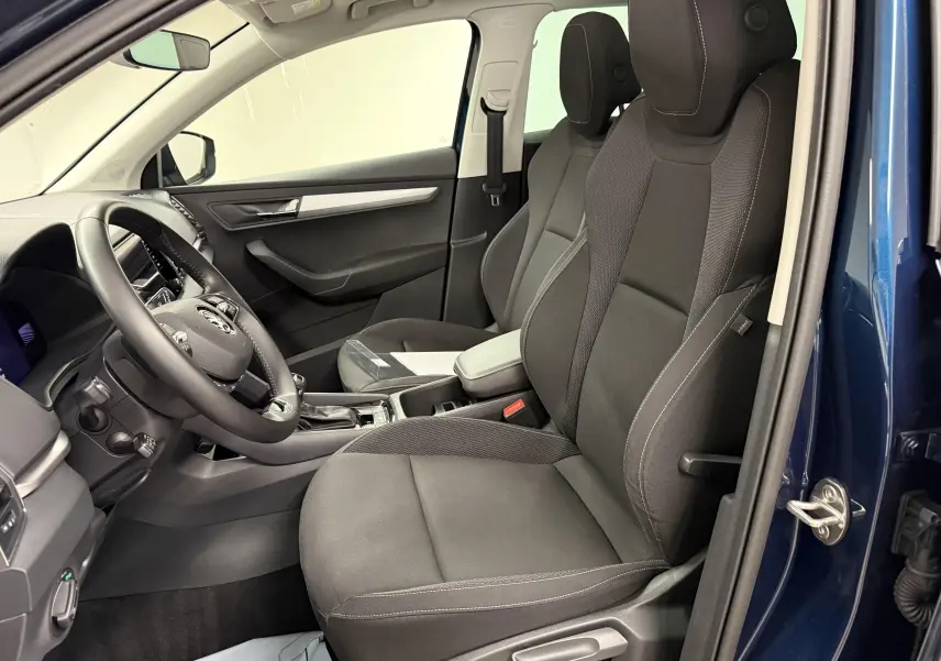 Vue intérieure côté conducteur du Skoda Karoq bleu lave 2023, sièges noirs et tableau de bord moderne.
