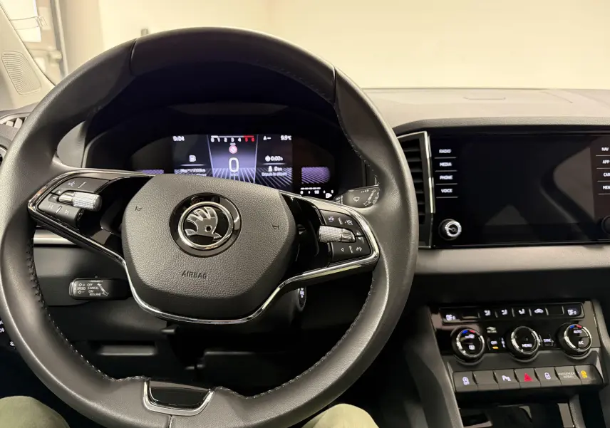 Vue intérieure centrée sur le volant noir de la Skoda Karoq 2023 avec tableau de bord numérique et console tactile.