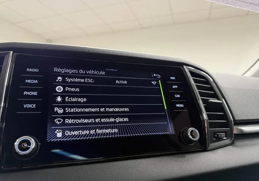 Écran tactile du tableau de bord du Skoda Karoq 2023 affichant les réglages du véhicule, vue intérieure côté conducteur.