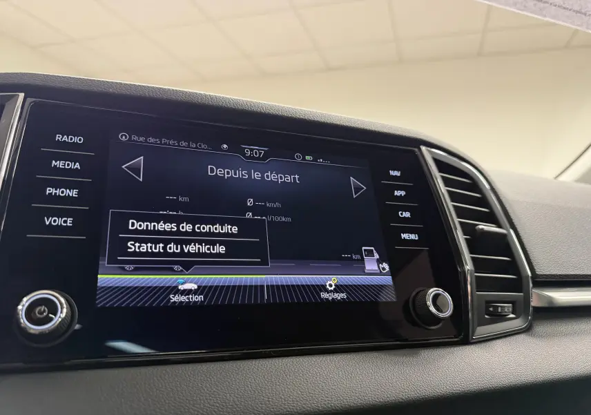 Écran tactile central du Skoda Karoq 2023 affichant les données de conduite, avec commandes autour et aérateurs à droite.