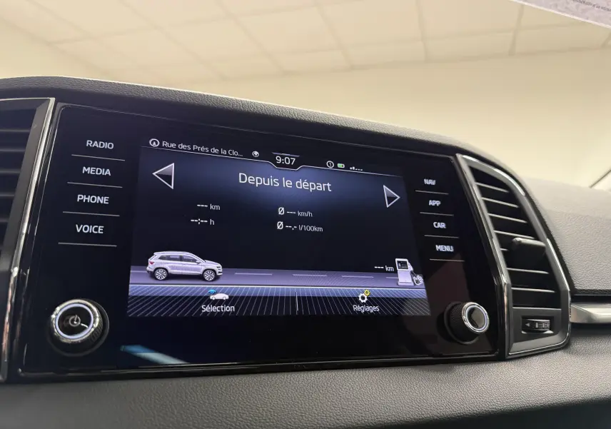 Écran tactile intérieur du Skoda Karoq affichant les données de trajet, avec commandes autour et tableau de bord gris.