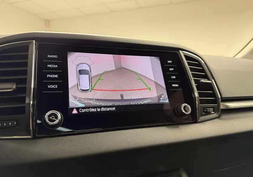 Écran central de la Skoda Karoq 2023 montrant la caméra de recul avec guidage de trajectoire en intérieur.