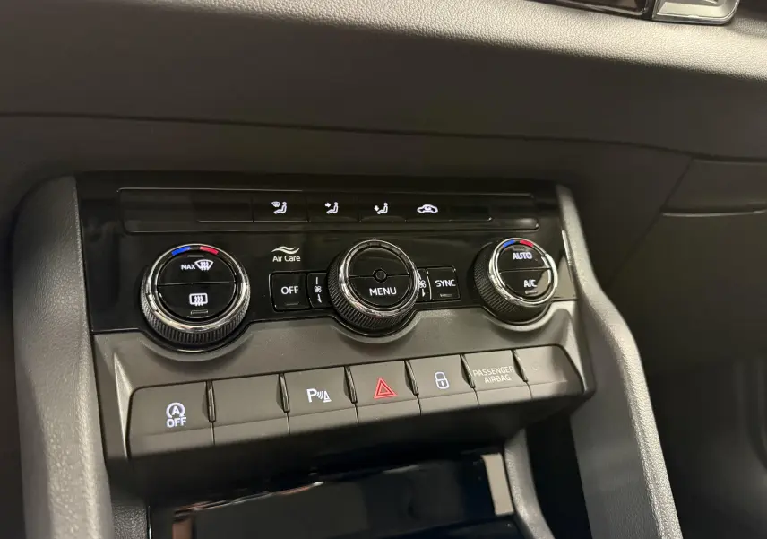 Gros plan sur la console centrale du Skoda Karoq 2023, montrant les commandes de climatisation et les boutons de fonction.