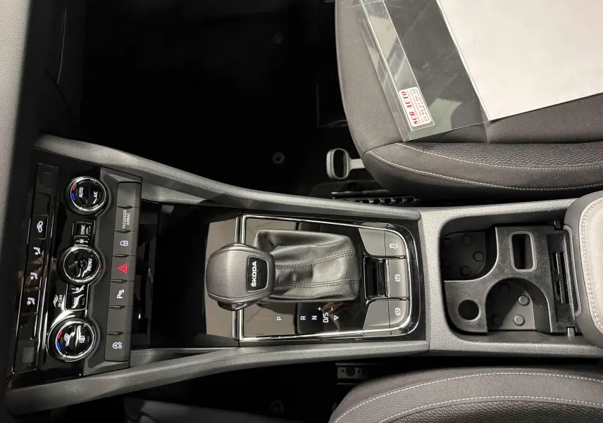Vue plongeante sur la console centrale du Skoda Karoq 2023, avec levier de vitesses automatique et commandes climatisation.