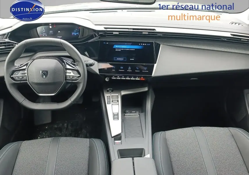 Vue intérieure avant de la Peugeot 308 SW 2025, tableau de bord et volant multifonction en noir et gris.