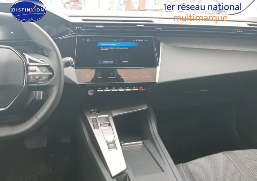Vue intérieure de la Peugeot 308 SW 2025, tableau de bord et console centrale avec écran tactile et volant multifonction.