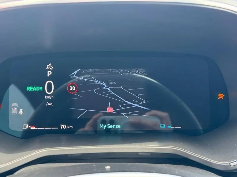 Affichage numérique du tableau de bord de la Renault Clio 1.6 E-Tech 145ch rouge, montrant la navigation et la vitesse à 0 km/h.