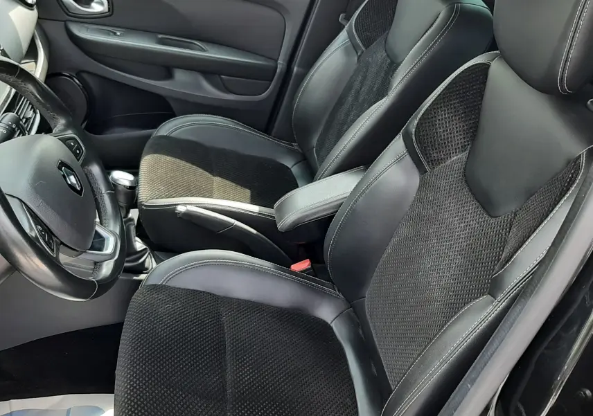 Vue intérieure côté gauche de la Renault Clio IV noire, mettant en valeur les sièges mixtes cuir et tissu avec surpiqûres blanches.