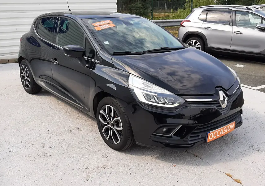Renault Clio IV noire vue en 3/4 avant droit, avec jantes alliage et plaque "OCCASION" orange visible.