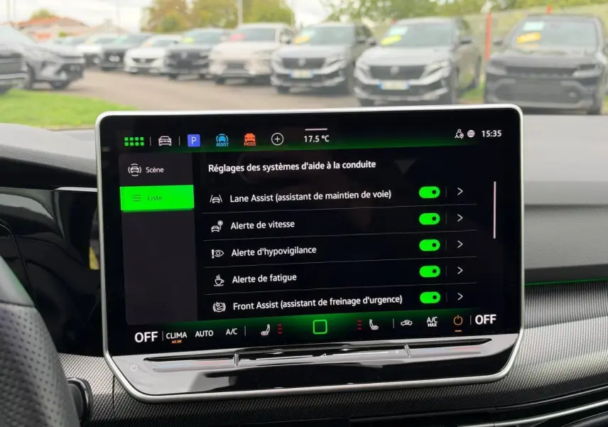 Vue intérieure sur l'écran tactile central affichant les aides à la conduite dans une Volkswagen Golf blanche Oryx nacrée.