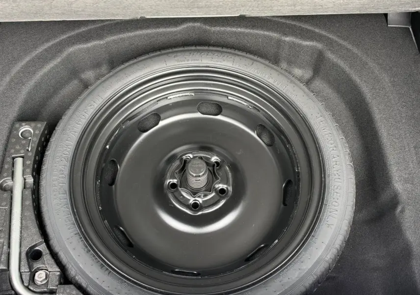 Roue de secours noire dans le coffre d'une Volkswagen Golf 1.5 eTSI EVO2 blanche, vue en plongée.
