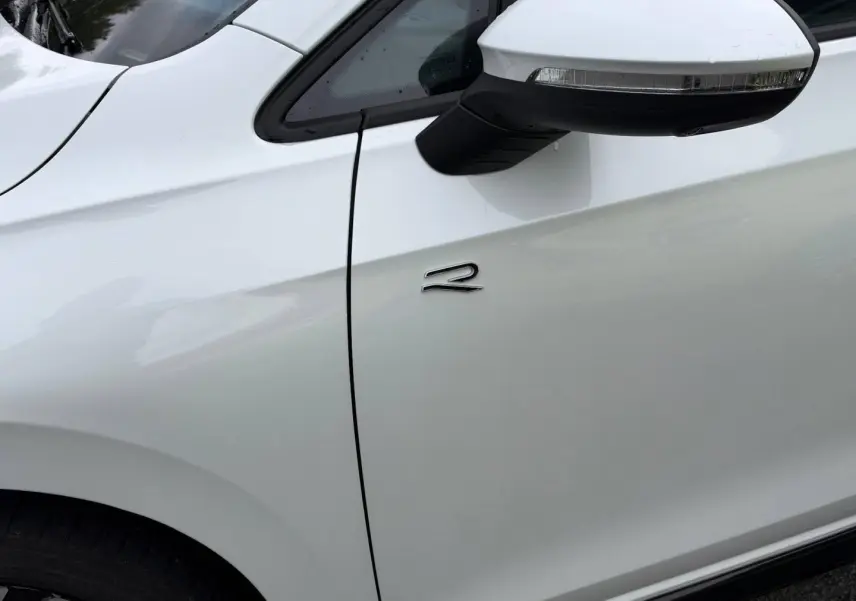 Détail du côté gauche d'une Volkswagen Golf R-Line blanche Oryx nacrée avec rétroviseur et logo R.