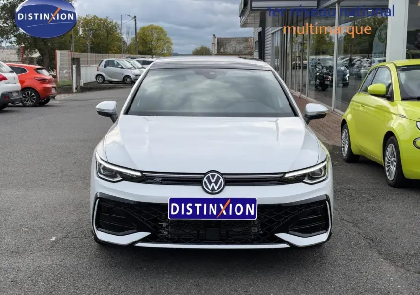 Vue frontale d'une Volkswagen Golf blanche Oryx nacrée avec calandre noire et logo VW bien visible.