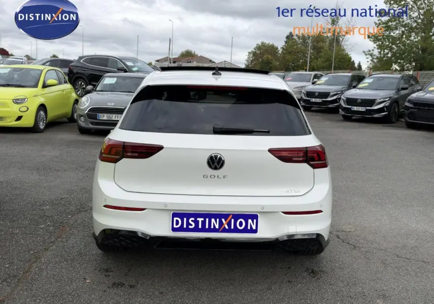 Vue arrière d'une Volkswagen Golf 1.5 eTSI EVO2 blanche Oryx nacrée avec vitres arrière surteintées sur un parking.
