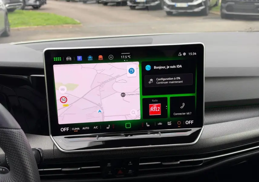 Vue intérieure centrée sur l'écran tactile du tableau de bord de la Volkswagen Golf blanc Oryx nacrée 2025.