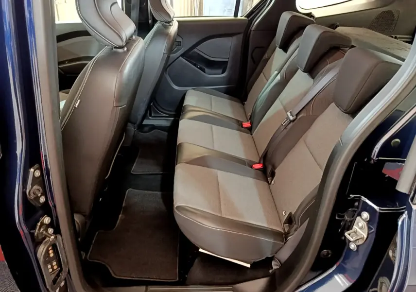 Vue latérale intérieure côté droit du Renault Kangoo bleu 2023, sièges arrière en tissu gris et noir avec ceintures de sécurité.