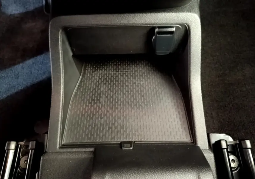 Gros plan sur le rangement central noir du Renault Kangoo bleu 2023, version Equilibre TCe 100, intérieur sobre et fonctionnel.