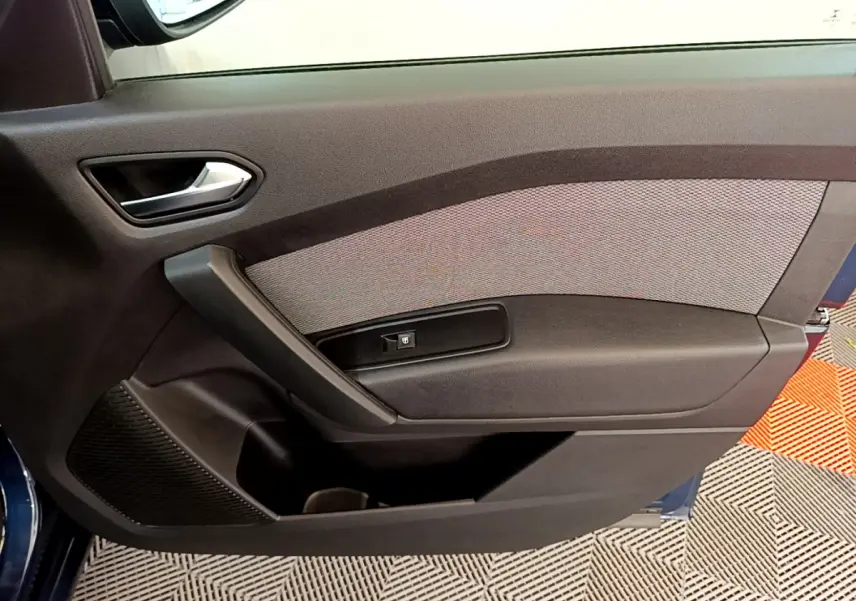 Porte intérieure côté gauche du Renault Kangoo Equilibre 2023 bleu, avec poignée argentée et bouton de lève-vitre.