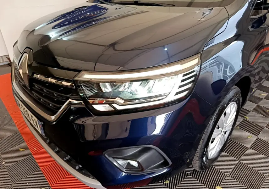 Vue 3/4 avant droit d'un Renault Kangoo bleu 2023 avec phares LED et calandre chromée visible.