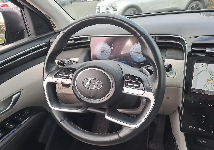 Vue intérieure centrée sur le volant cuir noir du Hyundai Tucson 2023 avec tableau de bord digital et écran tactile.