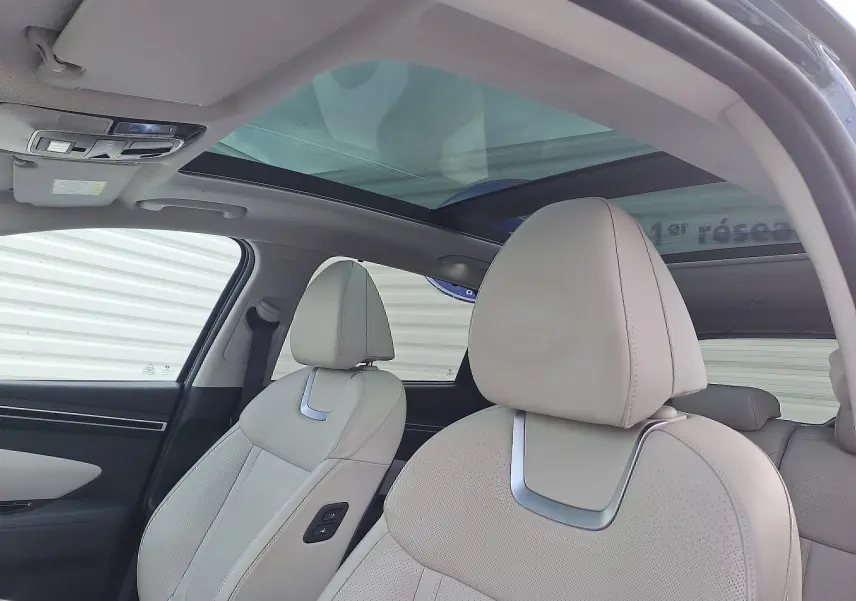 Intérieur beige clair du Hyundai Tucson 2023, vue côté gauche sur les sièges avant en cuir et toit panoramique vitré.