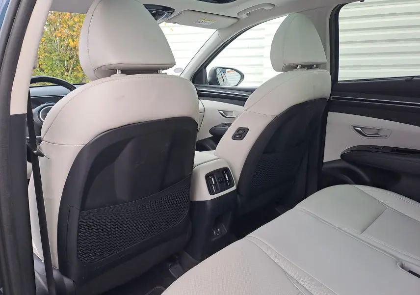 Vue arrière intérieure du Hyundai Tucson 2023 avec sièges cuir beige et commandes climatisation arrière visibles entre les sièges avant.