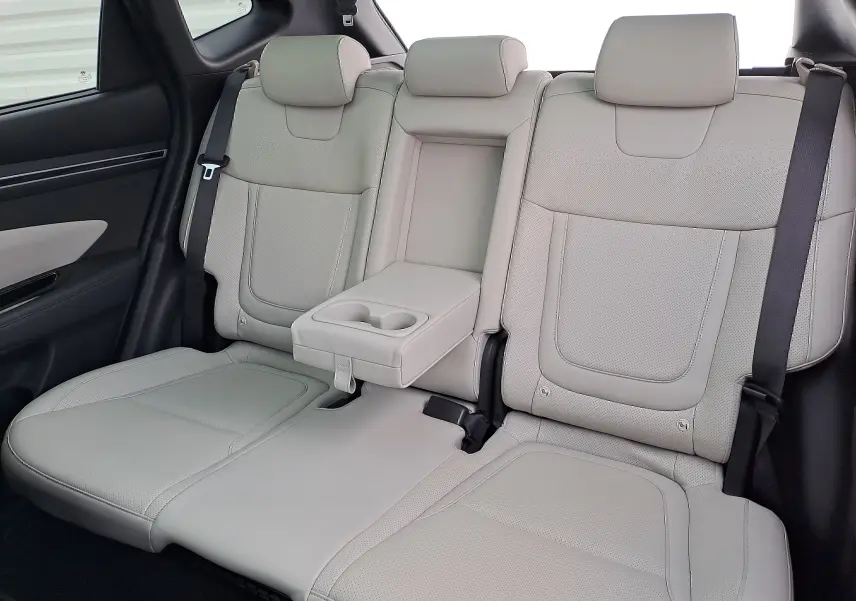 Vue rapprochée des sièges arrière en cuir beige du Hyundai Tucson 2023, avec accoudoir central et porte-gobelets intégrés.