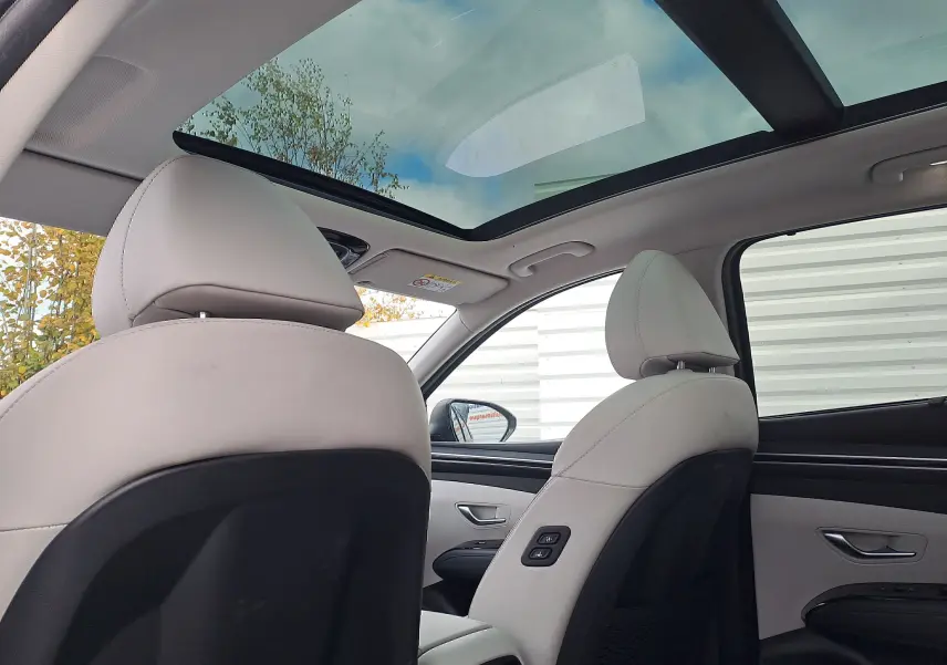 Vue intérieure arrière du Hyundai Tucson 2023 avec sièges cuir beige et toit panoramique vitré.
