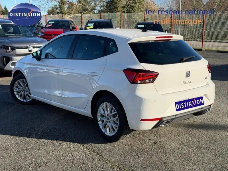 Vue 3/4 arrière droite d'une SEAT Ibiza 1.0 TSI 115cv FR blanche Nevada métal, avec jantes alliage et feux arrière LED.