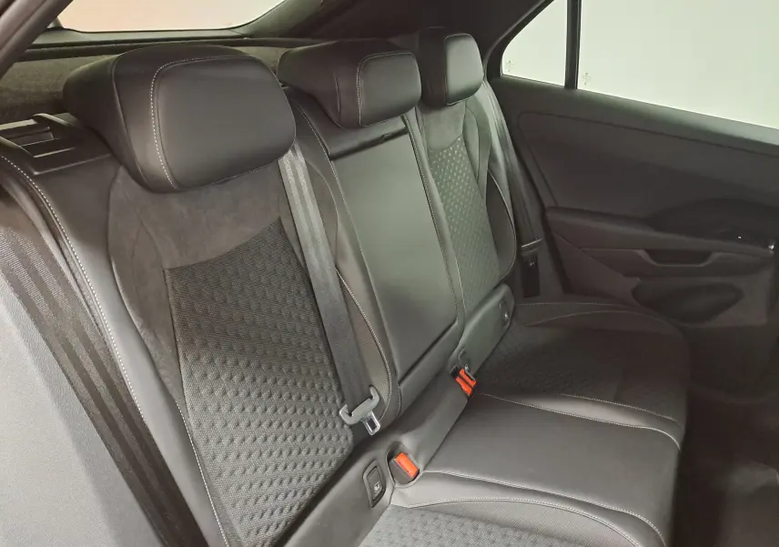 Vue intérieure du siège arrière droit du Volkswagen T-Roc 2026, revêtement noir avec surpiqûres contrastées et ceintures visibles.