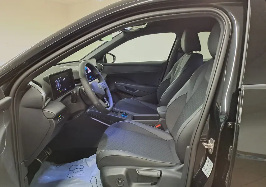 Vue intérieure côté conducteur du Volkswagen T-Roc 2026 noir ébène, avec sièges en tissu et tableau de bord digital.