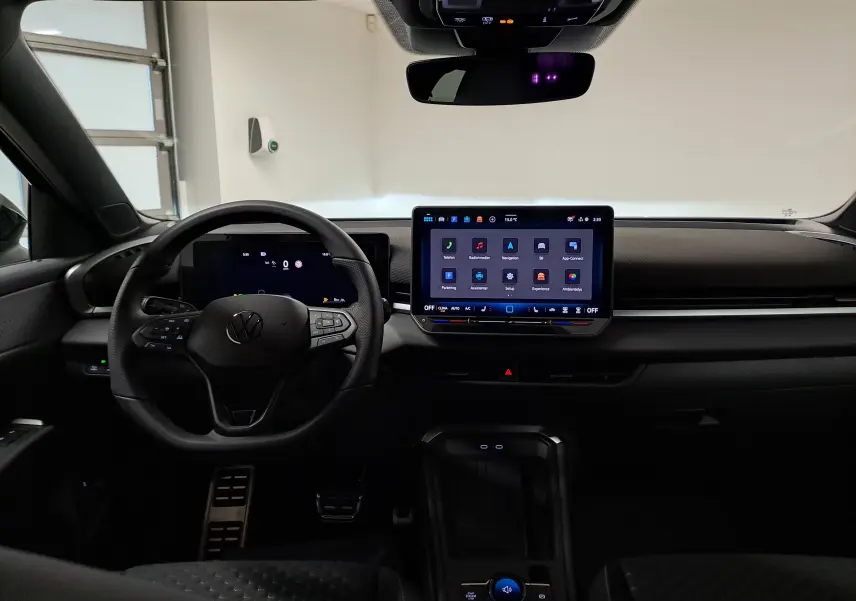 Vue intérieure frontale du tableau de bord noir du Volkswagen T-Roc 2026 avec écran tactile central et volant multifonction.
