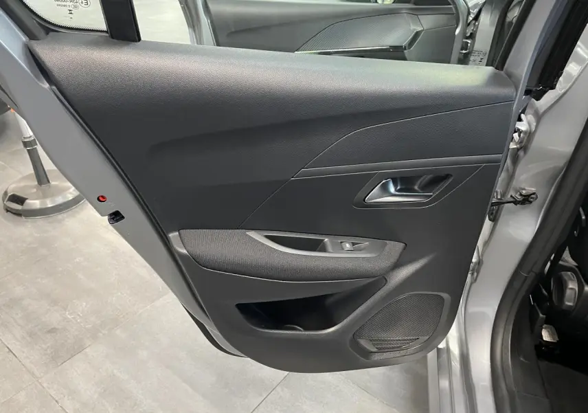Vue intérieure de la porte arrière droite gris clair de la Peugeot 208 2024 avec commande de vitre et haut-parleur intégré.