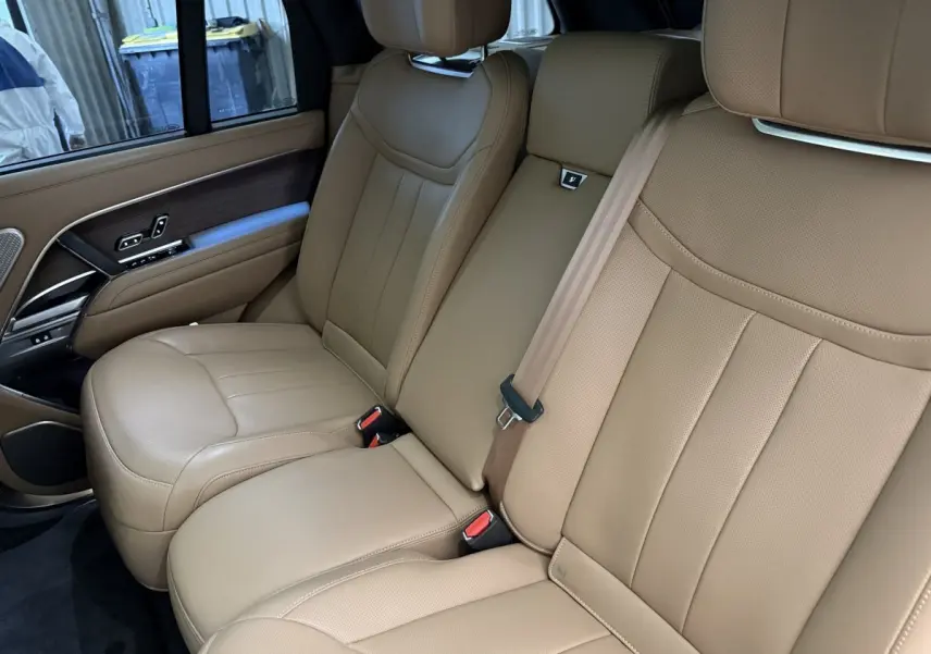 Vue intérieure côté droit des sièges arrière en cuir beige du Range Rover PHEV P550e Autobiography 2024.