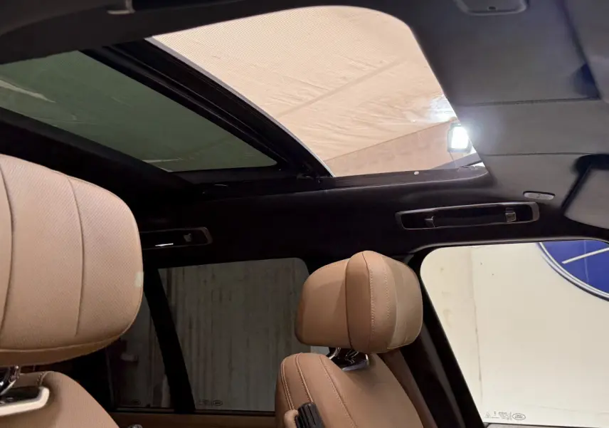 Vue intérieure du toit ouvrant panoramique et des appuie-têtes en cuir beige du Range Rover noir 2024.