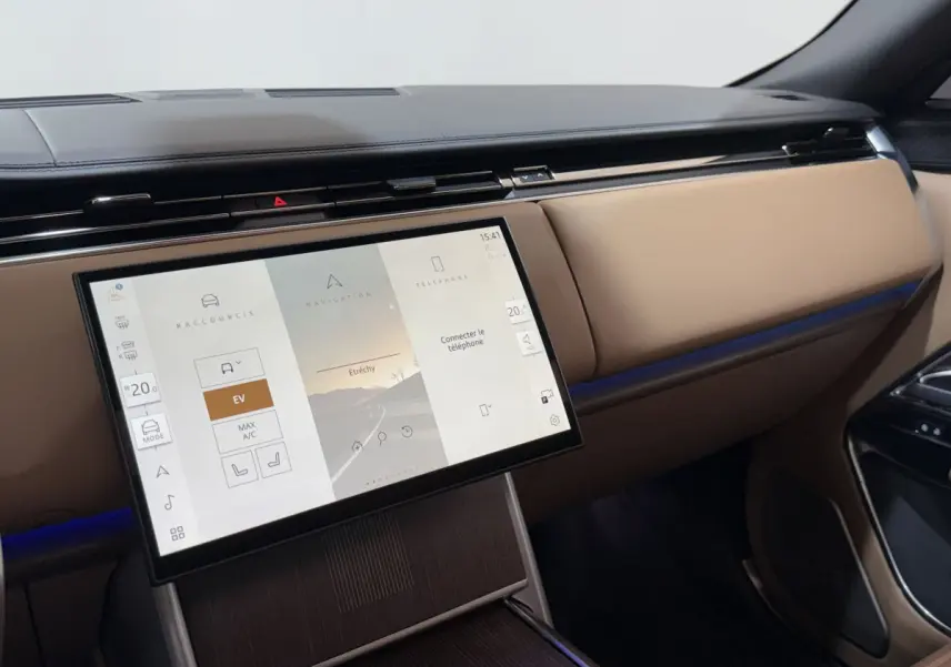 Vue intérieure du tableau de bord beige du Range Rover PHEV 2024 avec écran tactile central allumé.