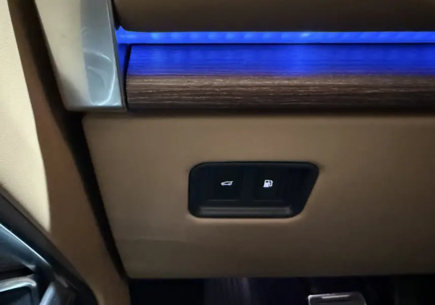 Détail intérieur montrant les boutons d'ouverture du coffre et de la trappe à carburant sur un Range Rover noir.