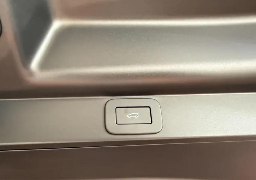 Bouton de fermeture électrique du coffre sur le panneau intérieur d’un Range Rover PHEV noir, vue rapprochée.