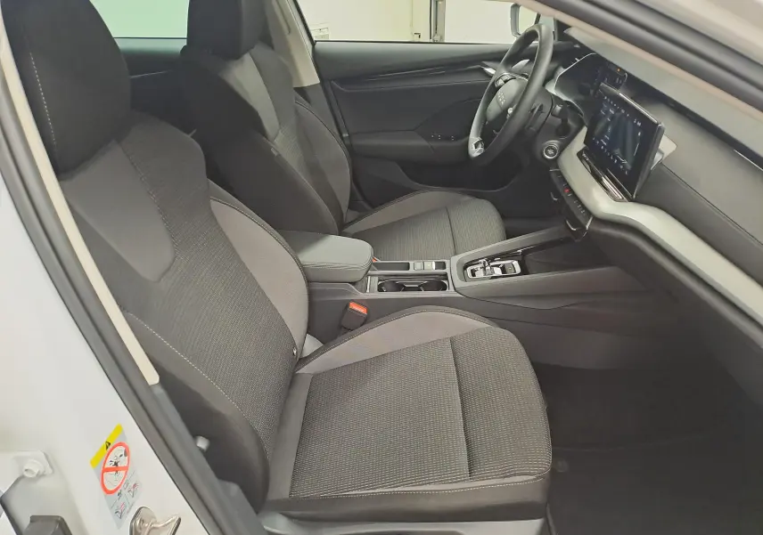 Vue intérieure côté conducteur de la Skoda Octavia Combi 2025, sièges tissu gris et tableau de bord moderne.
