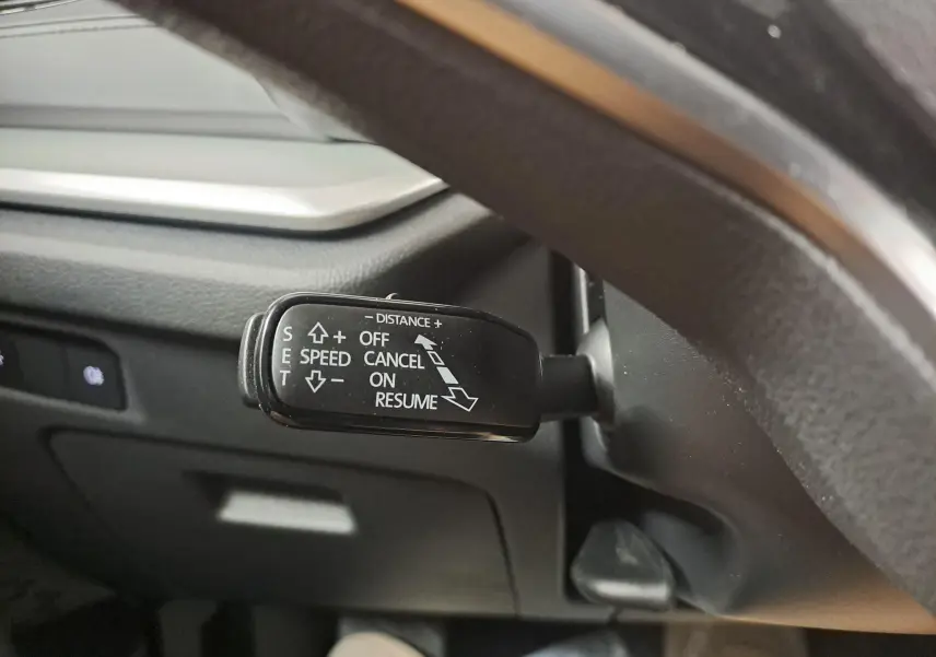 Gros plan sur le levier de régulateur de vitesse à gauche du volant dans une Skoda Octavia Combi blanc Moon.