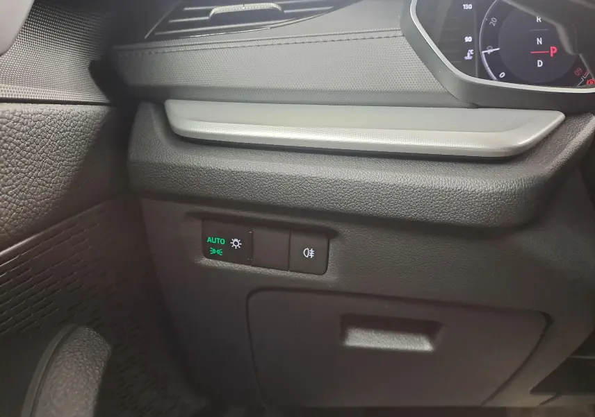 Détail intérieur côté gauche du tableau de bord de la Skoda Octavia Combi blanc Moon, avec commandes d’éclairage et indicateur digital.