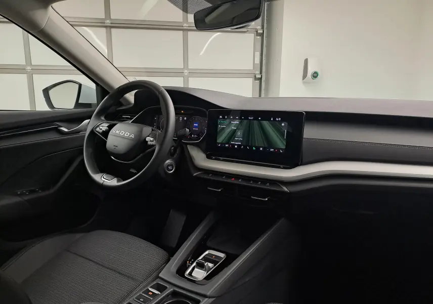 Vue intérieure côté conducteur de la Skoda Octavia Combi 2025, tableau de bord noir avec écran tactile central allumé.