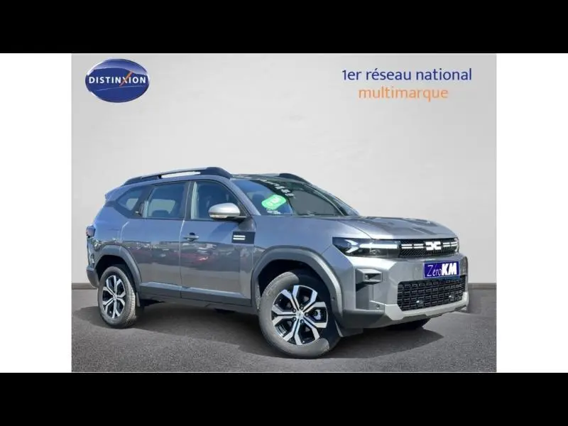 Vue 3/4 avant droit du Dacia Bigster gris métallisé avec barres de toit et jantes alliage distinctives.