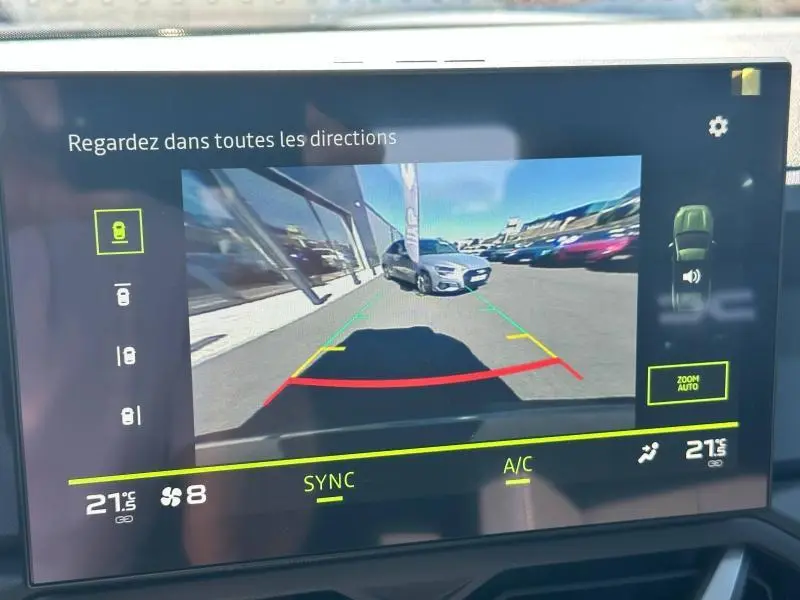 Écran tactile montrant la caméra de recul du Dacia Bigster blanc avec lignes de guidage colorées.