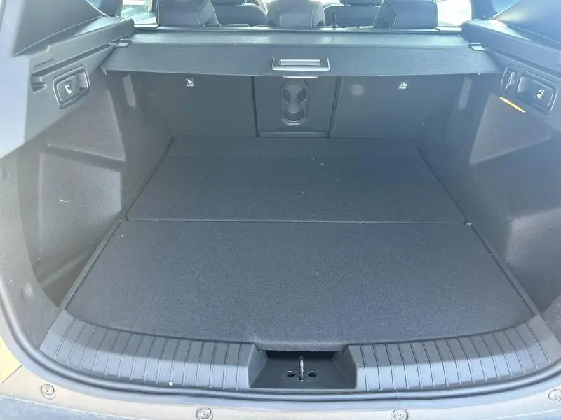 Vue intérieure du coffre noir du Dacia Bigster 2025, avec banquette arrière rabattable et trappe à skis visible.