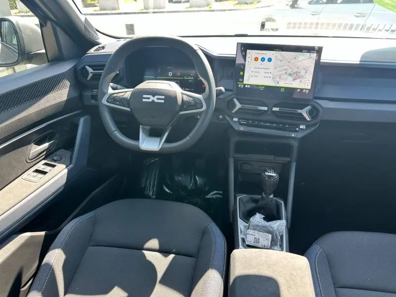 Vue intérieure avant du Dacia Bigster 2025, montrant le volant multifonction, écran tactile GPS et levier de vitesses manuel.