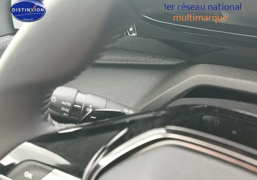 Détail intérieur du volant et du commodo d’éclairage de la Peugeot 308 SW gris sélénite, vue côté conducteur.