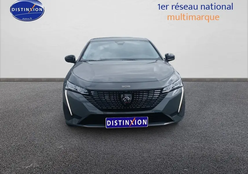 Vue frontale d'une Peugeot 308 SW gris sélénite avec calandre noire et feux LED verticaux allumés.
