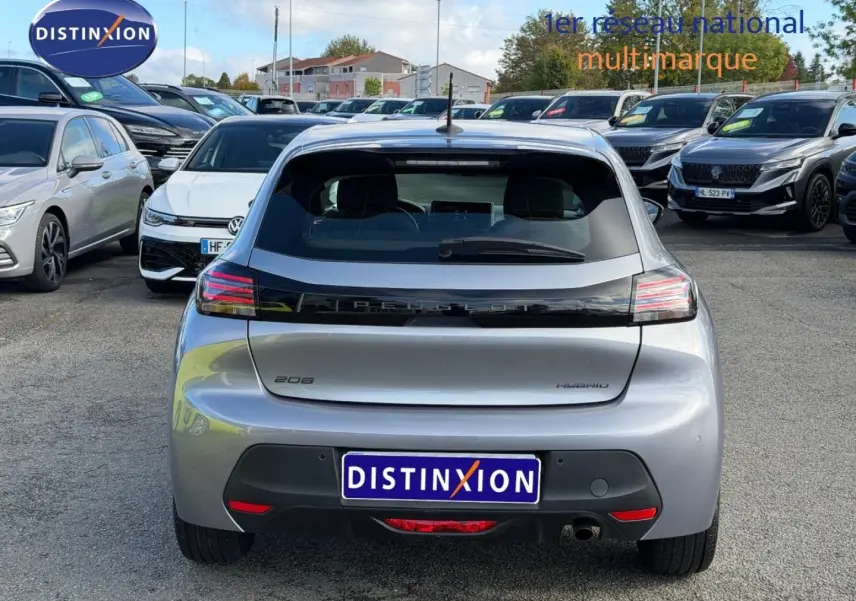 Vue arrière d'une Peugeot 208 hybride gris Artense garée dans un parking multimarque en extérieur.